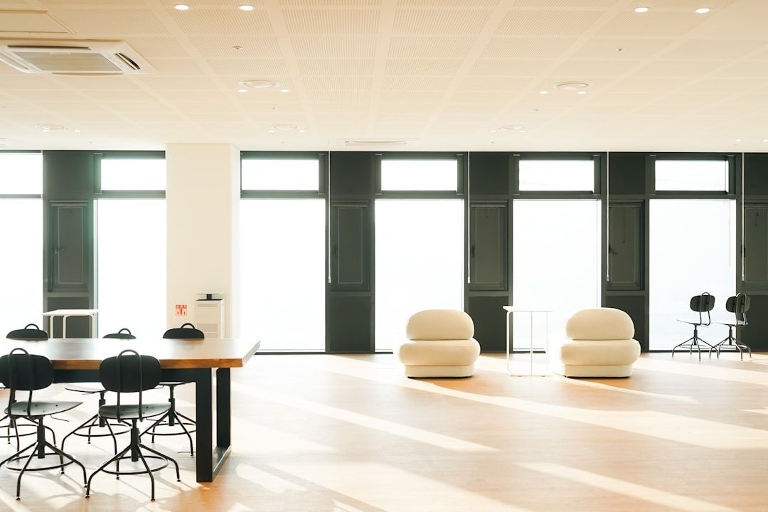 Bright open office with tables, chairs, lounge seats, and tall windows