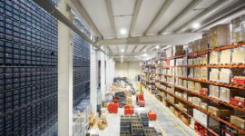 Warehouse aisle with component bins, pallets, and stocked storage racks